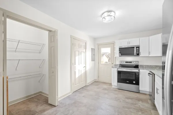 a large white kitchen with stainless steel appliances granite countertop a stove and a refrigerator