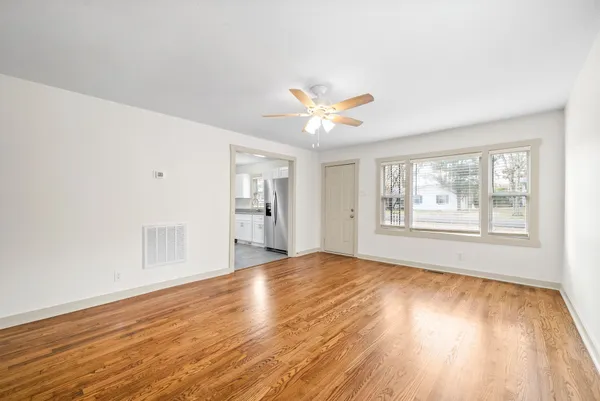 a view of an empty room with a window and wooden floor