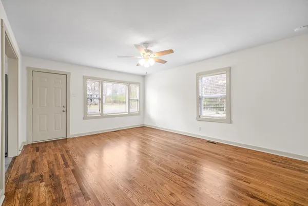a view of an empty room with wooden floor and a window