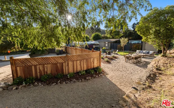 a view of a backyard with chairs and potted plants