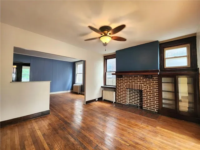 a view of an empty room with window and wooden floor