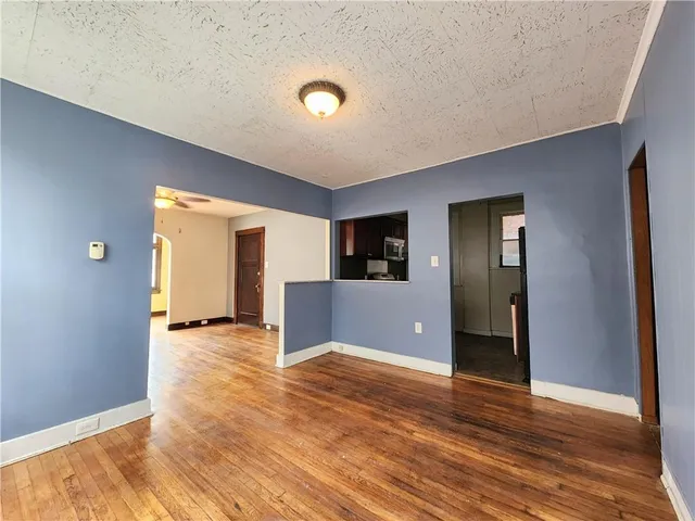 a view of a livingroom with wooden floor and kitchen space
