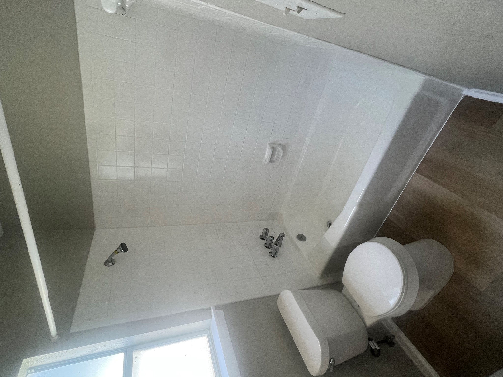 4620 Button Bend Road Austin, TX 78744 - Photo 19 of 22 A well-maintained bathroom provides a pristine tub and shower combination with light wood-tone flooring.
