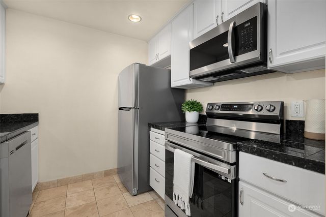 a kitchen with stainless steel appliances granite countertop white cabinets a refrigerator and a stove top oven