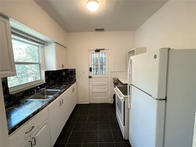 a kitchen with a refrigerator a sink and wooden floors