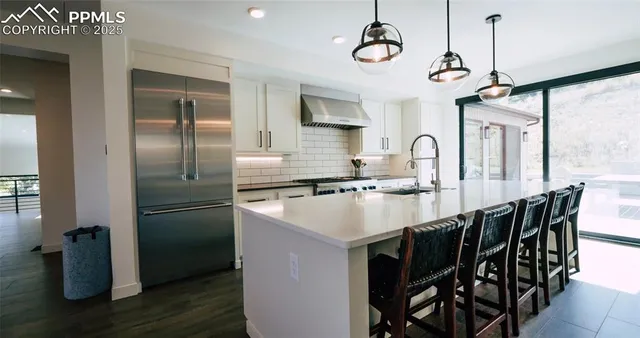 a kitchen with stainless steel appliances granite countertop a sink a refrigerator and a table