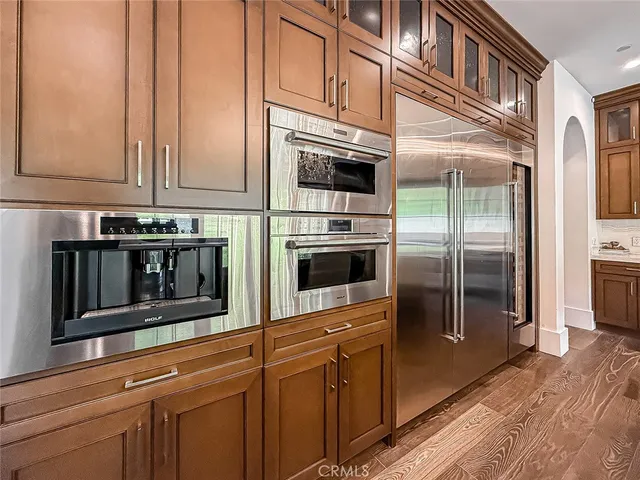 a kitchen with stainless steel appliances granite countertop a refrigerator a stove and a sink with wooden floor