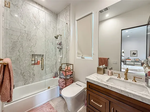 a bathroom with a granite countertop sink a toilet a mirror and bathtub