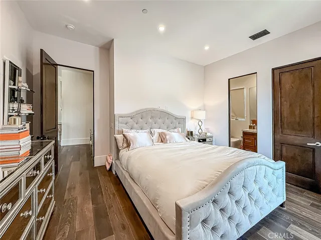 a bedroom with a bed and a flat tv screen on a dresser