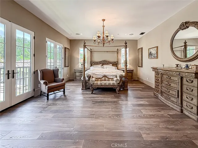a spacious bedroom with a bed a chandelier and dresser
