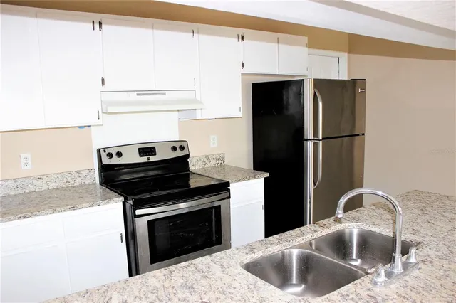 a kitchen with stainless steel appliances granite countertop a refrigerator and a sink