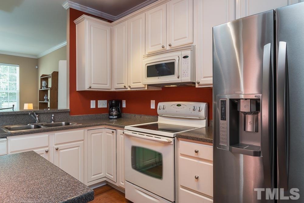 7839 Silverthread Lane Raleigh, NC 27617 - Photo 4 of 23 a kitchen with white cabinets and stainless steel appliances