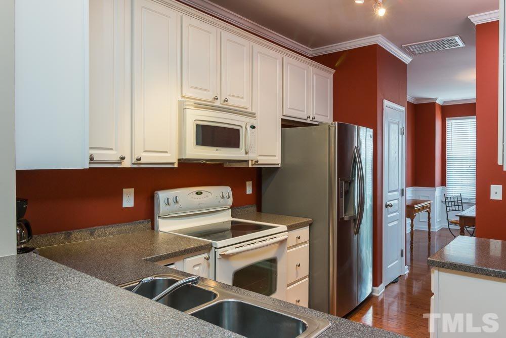 7839 Silverthread Lane Raleigh, NC 27617 - Photo 23 of 23 a kitchen with stainless steel appliances a stove a refrigerator sink and white cabinets