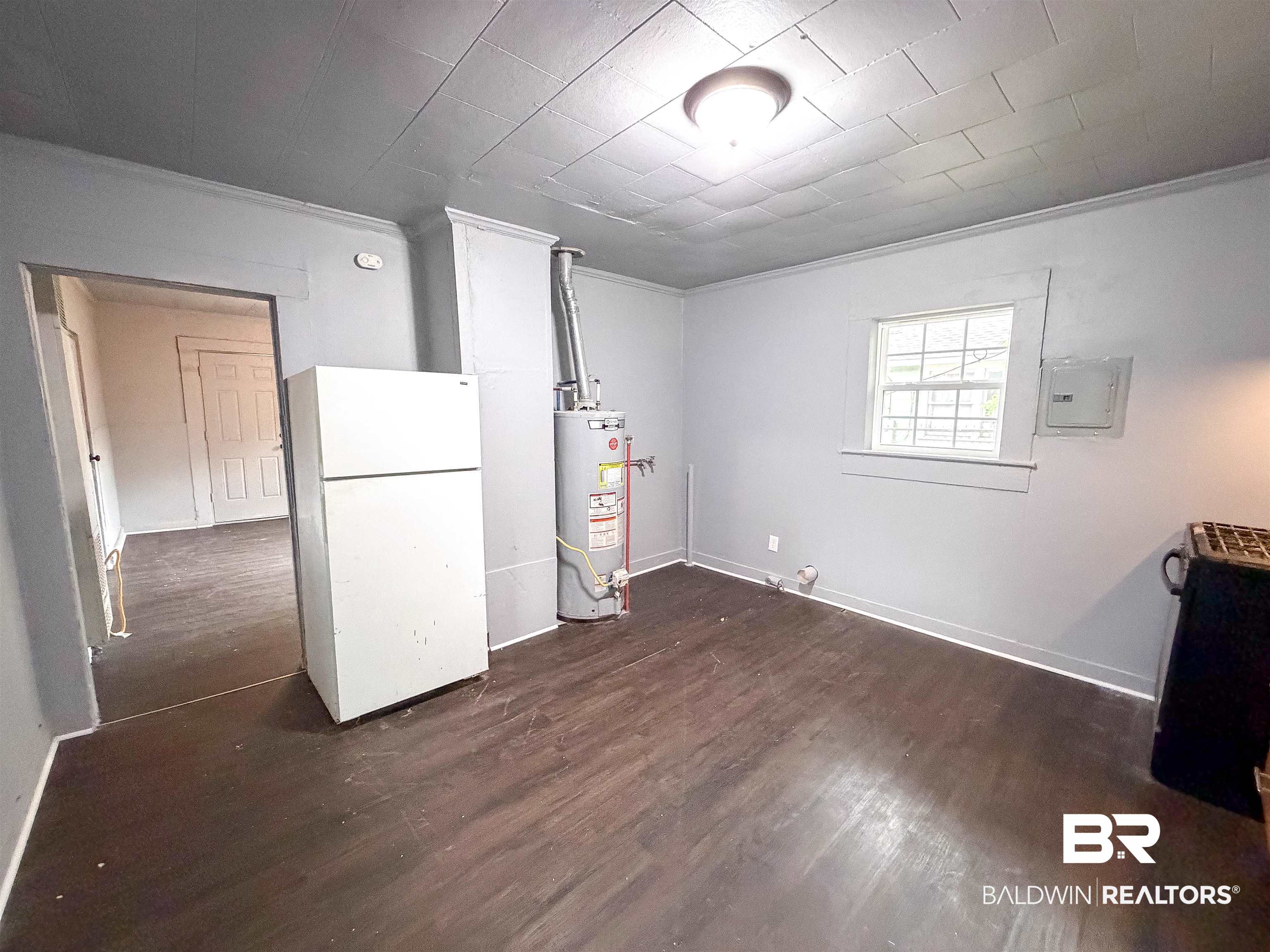 38 Flock Avenue Mobile, AL 36610 - Photo 5 of 27 Spacious room featuring dark wood-finish flooring, light gray wall paint, and a window for natural illumination