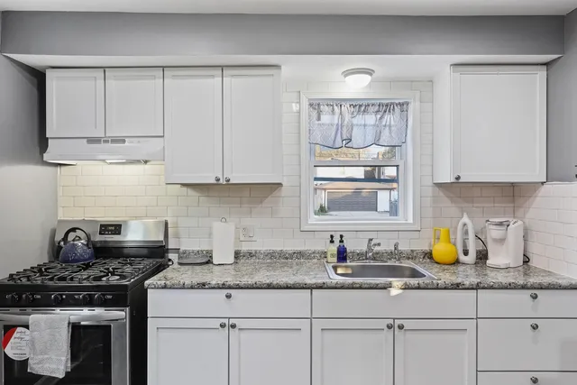 a kitchen with granite countertop white cabinets and a stove