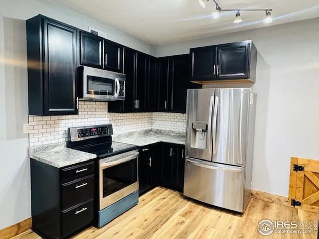 a kitchen with stainless steel appliances granite countertop a refrigerator stove a sink dishwasher and microwave