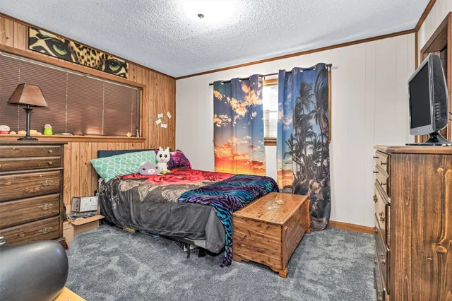 a bedroom with a bed table and a flat screen tv