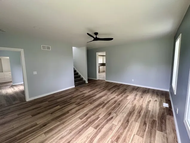 a view of an empty room with wooden floor and window