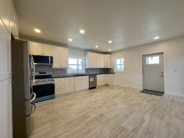 a large kitchen with stainless steel appliances granite countertop a stove a sink a refrigerator and a microwave