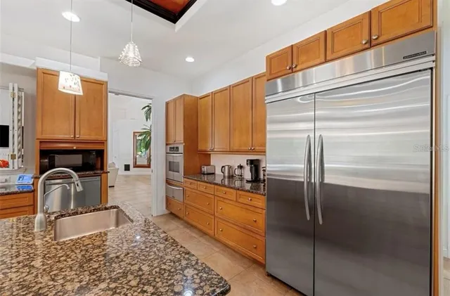 a kitchen with stainless steel appliances granite countertop a refrigerator a stove and a sink with granite countertops