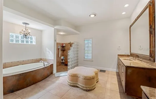 a spacious bathroom with a tub sink and mirror