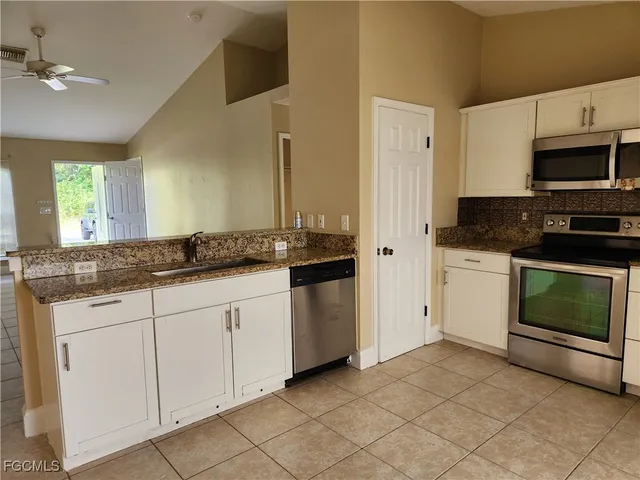 a kitchen with granite countertop white cabinets stainless steel appliances and sink