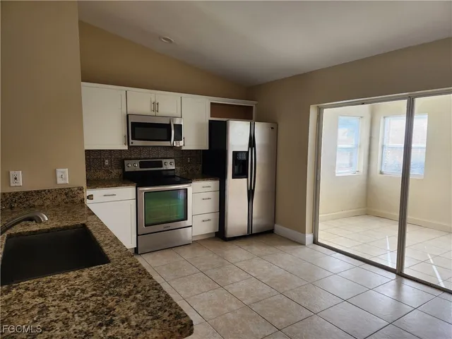 a kitchen with granite countertop a refrigerator and a stove