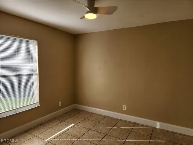 an empty room with a ceiling fan and window