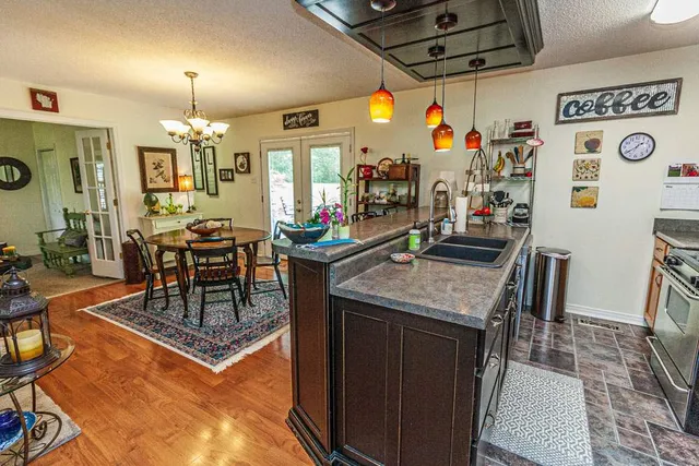 a kitchen with stainless steel appliances granite countertop a stove a refrigerator a dining table and chairs with the wooden floor