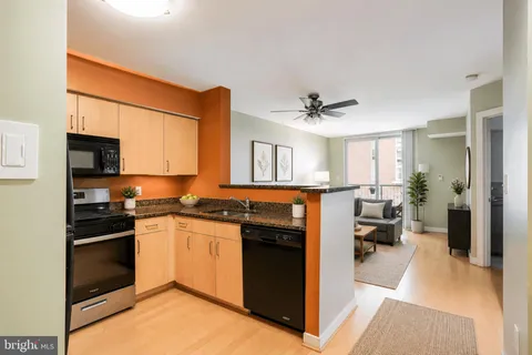 a kitchen with stainless steel appliances granite countertop a stove top oven a sink dishwasher a refrigerator and white cabinets with wooden floor