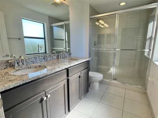 a bathroom with a granite countertop sink toilet and shower
