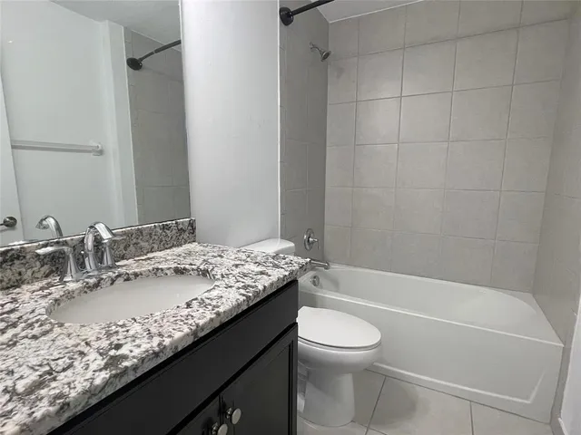a bathroom with a granite countertop sink a toilet and bathtub