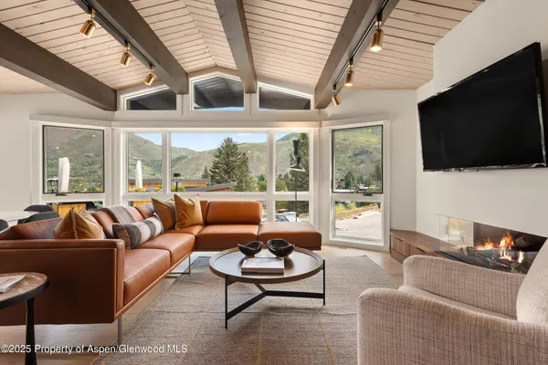 a living room with furniture a flat screen tv and a large window