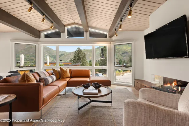 a living room with furniture a flat screen tv and a large window