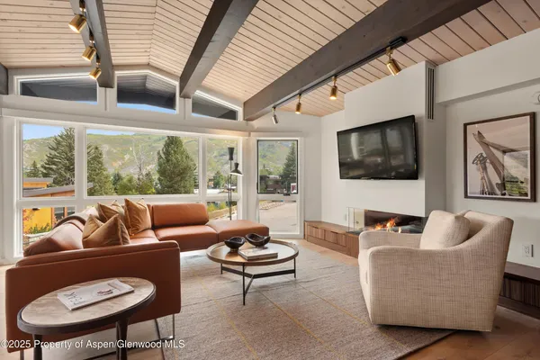 a living room with furniture floor to ceiling window and a flat screen tv