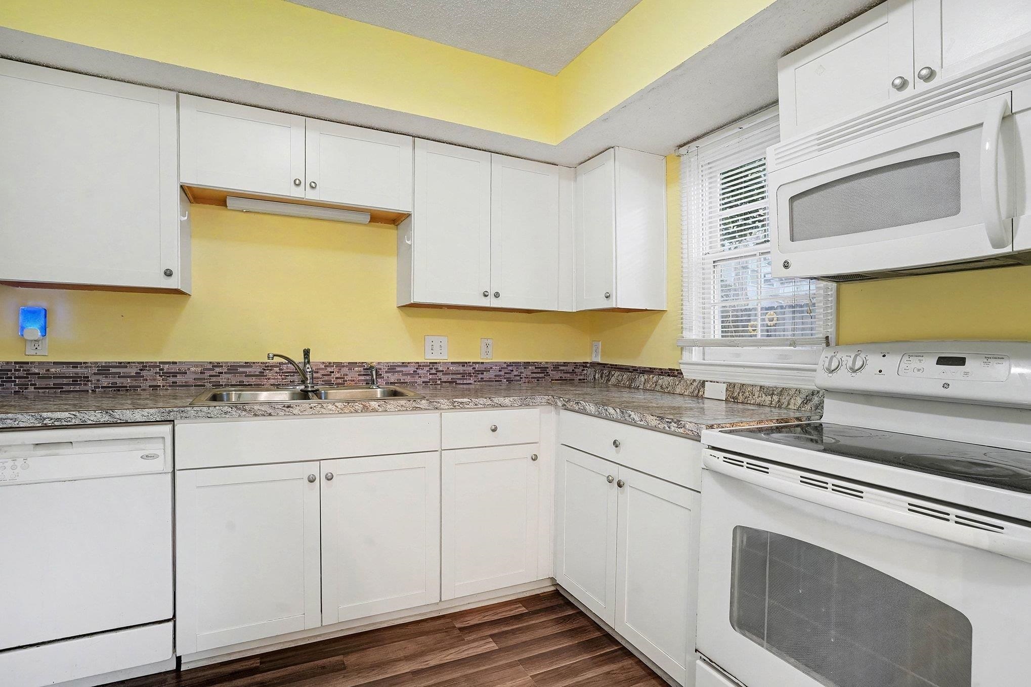 513 65th Avenue North, Unit I Myrtle Beach, SC 29572 - Photo 11 of 21 Kitchen featuring white appliances, white cabinetry, a textured ceiling, and light countertops
