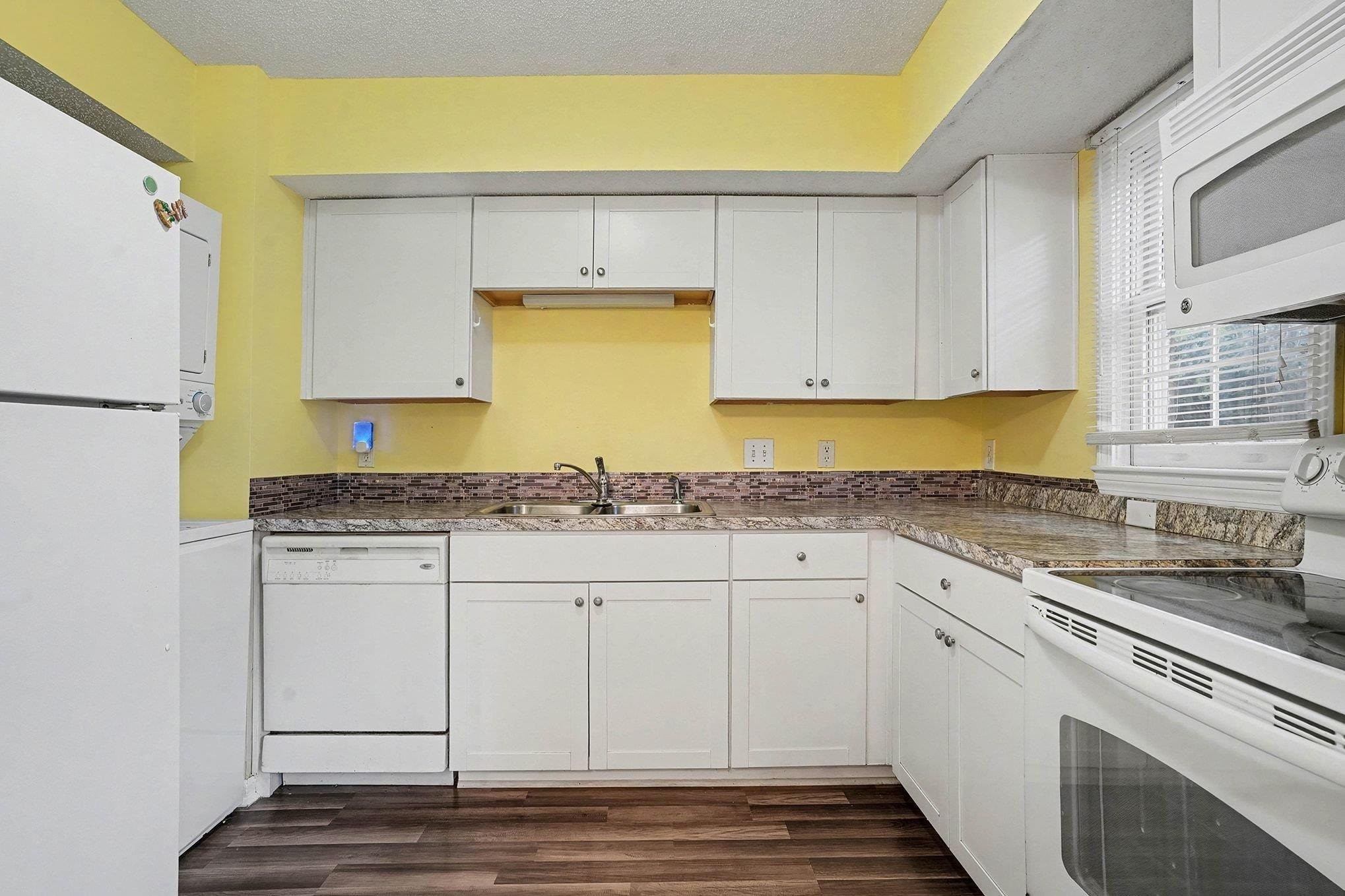 513 65th Avenue North, Unit I Myrtle Beach, SC 29572 - Photo 9 of 21 Kitchen featuring white appliances, white cabinetry, dark LVP flooring, and a textured ceiling