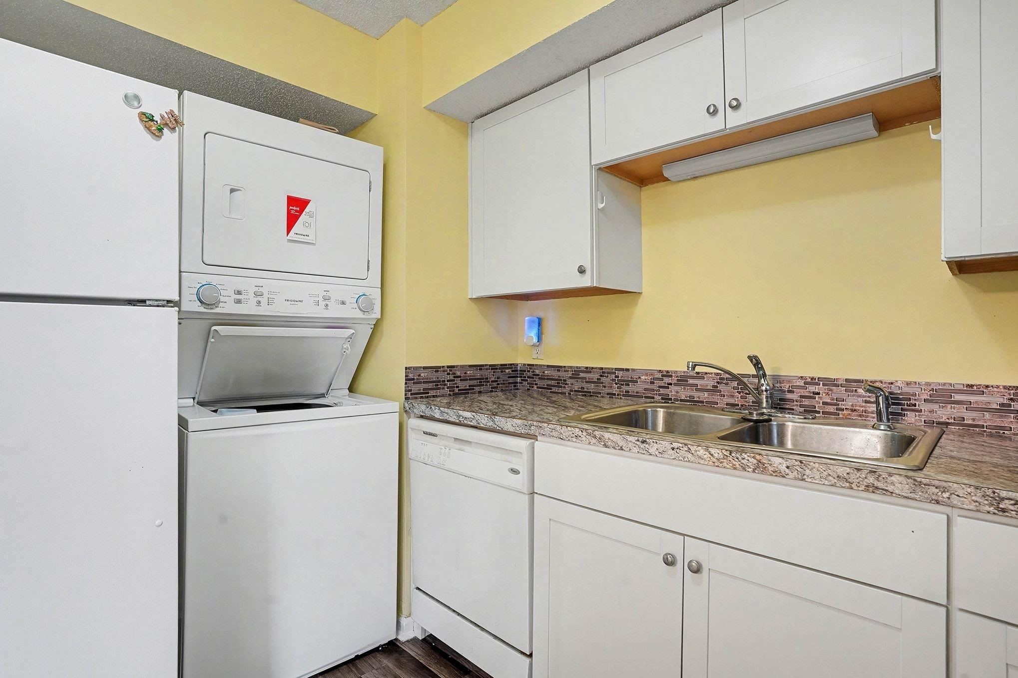 513 65th Avenue North, Unit I Myrtle Beach, SC 29572 - Photo 10 of 21 Kitchen with white appliances, white cabinetry, stacked washing machine and dryer, and light countertops