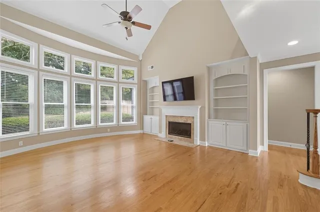 a view of an empty room with wooden floor fireplace and a window
