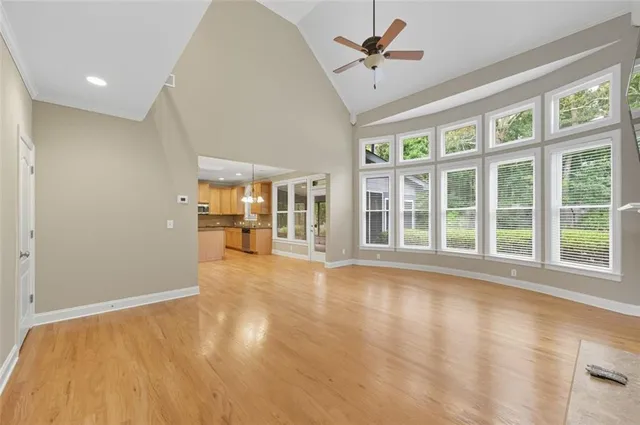a view of an empty room with wooden floor and a window