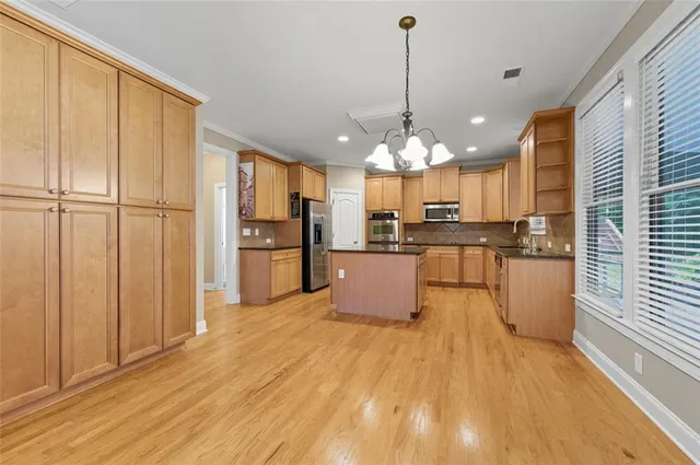 a large kitchen with kitchen island granite countertop wooden floor stainless steel appliances and cabinets
