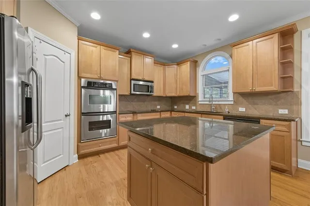 a kitchen with stainless steel appliances granite countertop a refrigerator a sink and white cabinets