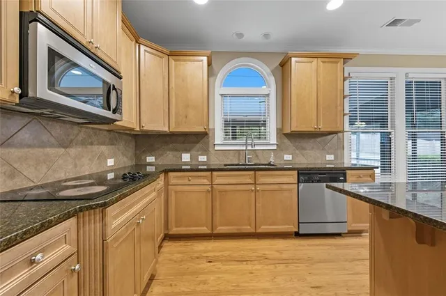 a kitchen with stainless steel appliances granite countertop a stove a sink and a microwave
