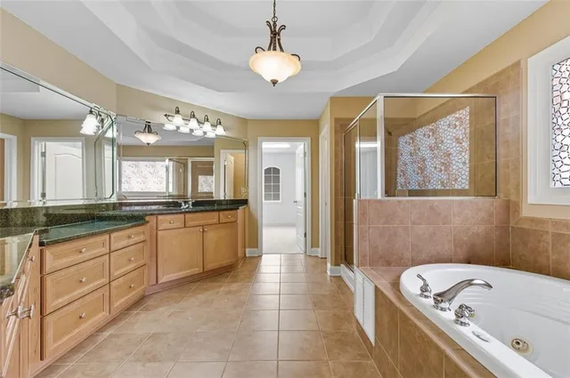 a large spacious bathroom with a granite countertop sink a mirror a bathtub and shower