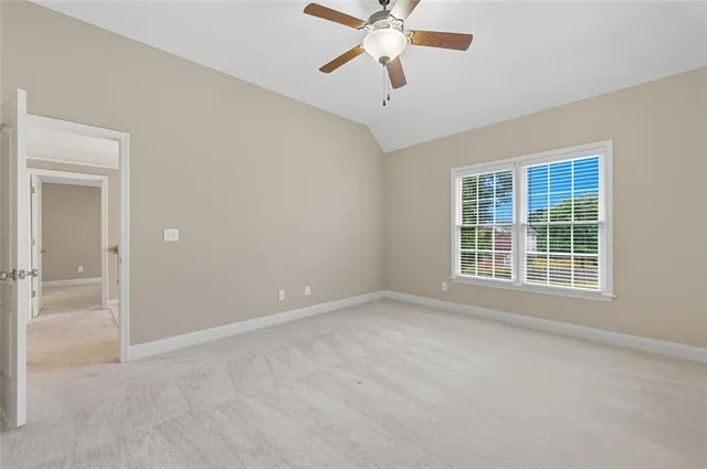 an empty room with chandelier fan and windows
