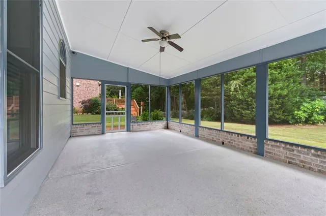 a view of an empty room with windows and ceiling fan