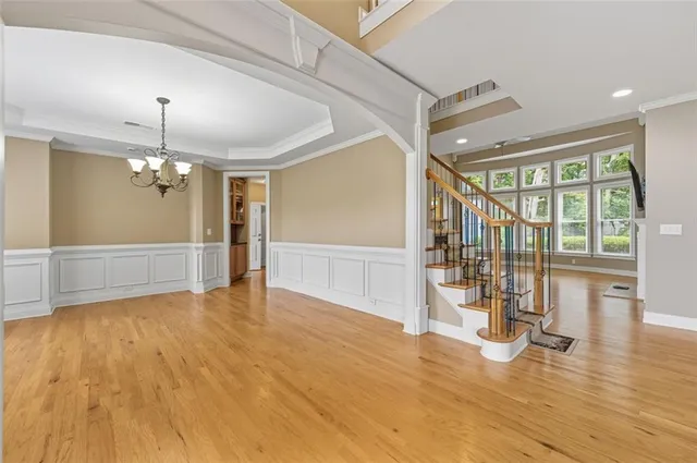 a view of an empty room with wooden floor kitchen view and a window