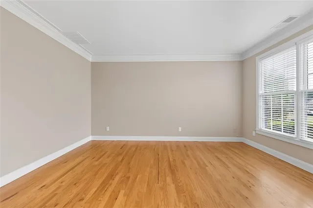 a view of an empty room with wooden floor and a window