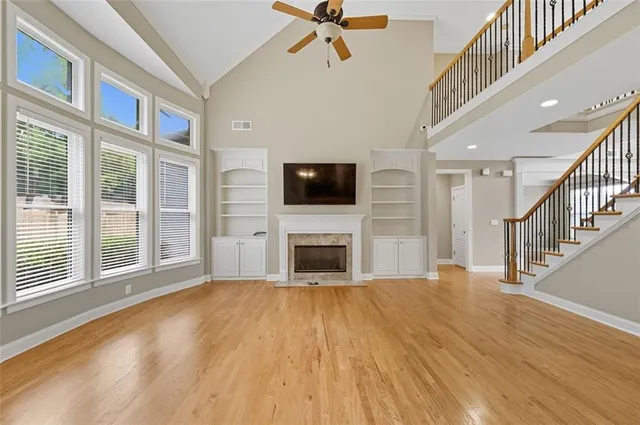 a view of a livingroom with a fireplace a ceiling fan and windows