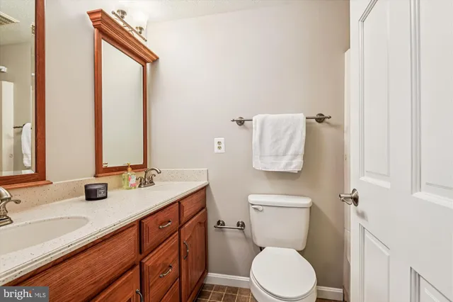 a bathroom with a granite countertop toilet sink and mirror